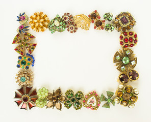 Woman's Jewellery. Frame with old vintage brooches. Beautiful bright rhinestones brooches on white....