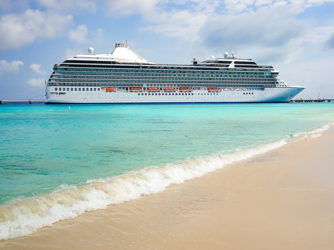 Cruise ship docked close to tropical beach.