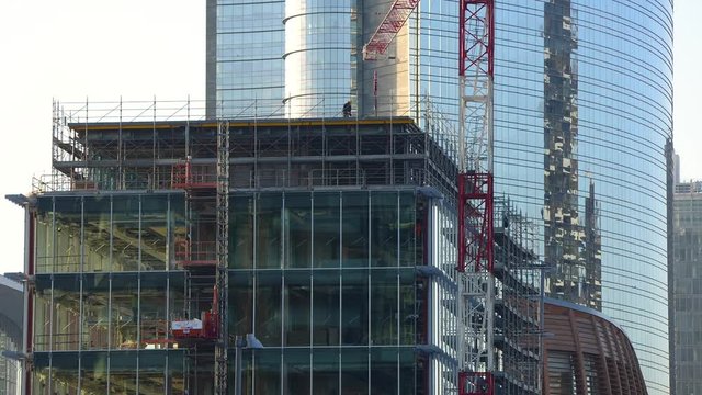 Uomini al lavoro in cantiere con gru di sollevamento lavorano ad un palazzo a pi&ugrave; piani in Milano Centro