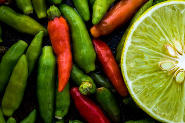 Half lemon on wooden table with red and green chili