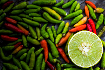 Half lemon on wooden table with red and green chili