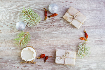 Рождественская композиция. Рождественские подарки, еловые ветки, свеча, елочные шары и сушеные ягоды шиповника