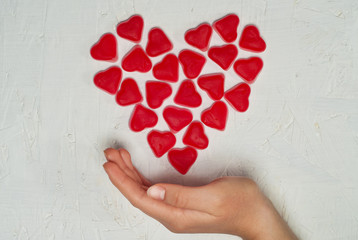 Woman's hand with heart made from jelly sweets on white background