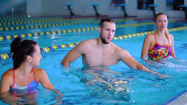 Three young people doing water exercises on the trainers in the swimming pool