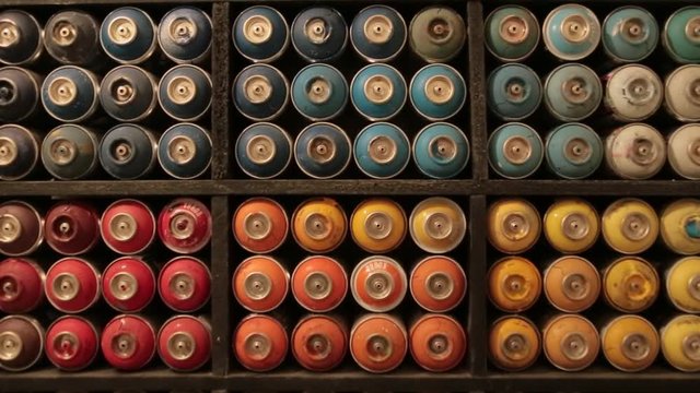 Close up view of the shelf with used multicolored graffiti spray cans. Art, artistic style. Inside shooting.