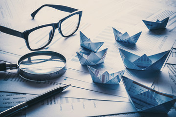 Glasses and pen with boats made of paper graph.