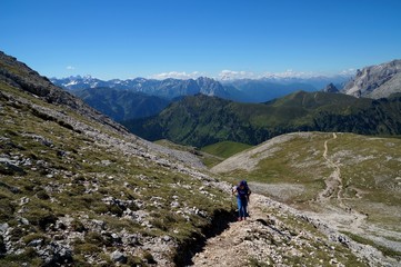 Fototapeta na wymiar Wanderin bergauf auf Plattkofel im Hintergrund herrliches Dolomiten Panorama
