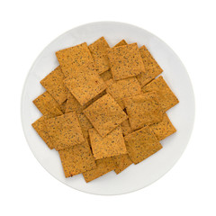 Thin gourmet snack crackers on a white plate top view.