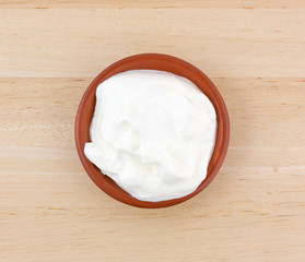 Sour cream in a small bowl on a wood table.