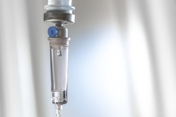 A drop on focus in intravenous drip on defocused pale white background, infusion dripping drops....