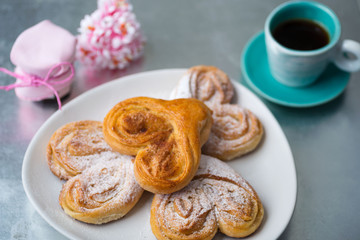 Buns with cinnamon and powdered sugar with coffee and a jar of j