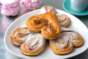 Obraz na płótnie Canvas Buns in the form of heart with cinnamon and powdered sugar with