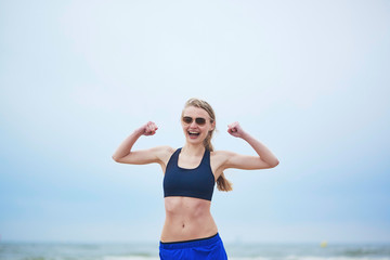 Healthy fitness runner girl showing her biceps