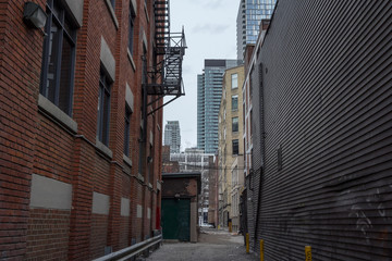 Picture of a dilapidated impasse street with the skyscraper skyline of Toronto in the background
