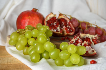Red and green grapes with pomegranate on a kitchen table