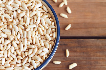 Puffed rice cereal in bowl on wooden background. Top view with copy space
