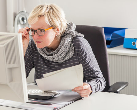 Blonde Angestellte im B&uuml;ro schaut konzentriert in den Computer 