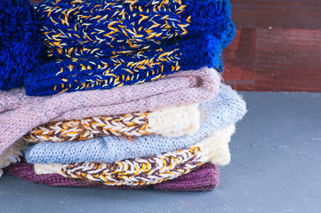 pile of multicolored knitted woolen scarves and warm hats