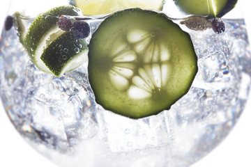 Glass of gin tonic with ice, cucumber and lime and white background - obrazy, fototapety, plakaty