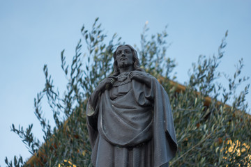 Jesus Christ statue with olive tree in the background