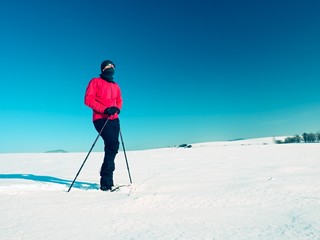 Fototapeta na wymiar Winter tourist with snowshoes walk in snowy drift. Hiker in pink sports jacket
