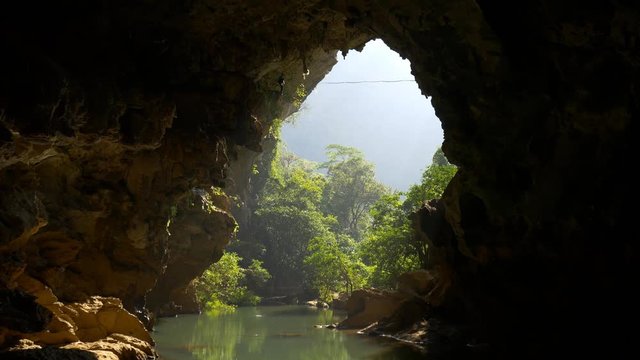 Tightrope walker in mountain cave with tropical forest on background