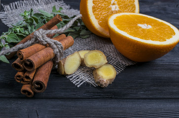 Orange fruit with cinnamon,ginger, mint on burlap and wooden texture background	