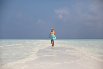 Fototapeta na wymiar Beautiful pregnant woman is walking on sand bank, Maldives