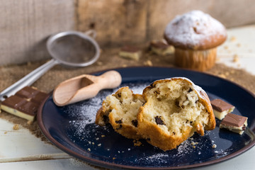 Muffins powdered by sugar on white blue plate and natural backgr
