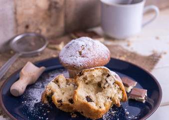 Muffins powdered by sugar on white blue plate and natural backgr