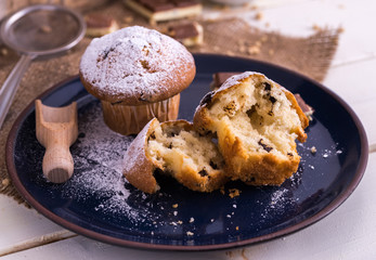 Muffins powdered by sugar on white blue plate and natural backgr