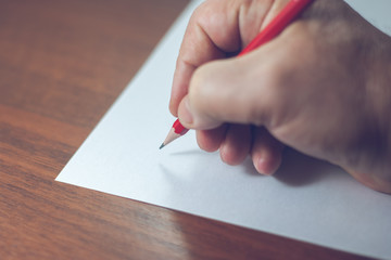 A close photo of a persons writing a letter with a pencil