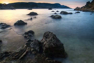 Long exposure seascape at sunrise. View of the cliff into the sea and distant islands. Paleokastrica. Corfu. Ionian archipelago. Greece.