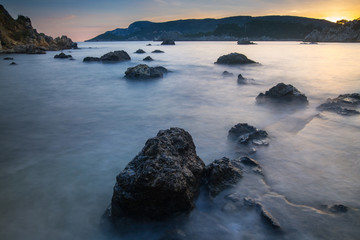 Long exposure seascape at sunrise. View of the cliff into the sea and distant islands. Paleokastrica. Corfu. Ionian archipelago. Greece.