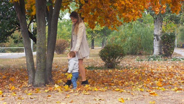 4K footage of cute baby boy learning how to walk with mother at park and falling down