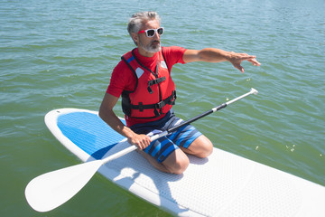 mature attractive rider contemplating nature sitting on paddle board