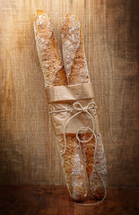 Fresh baguettes in paper on wooden vintage background