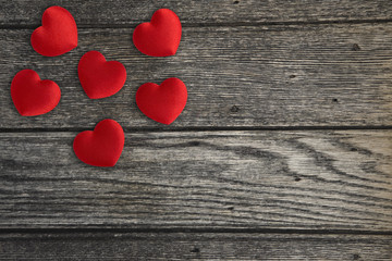 Red fabric rose petals on a wooden background