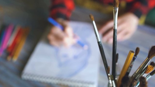 Young woman artist painting scetch on paper notebook with pencil closeup