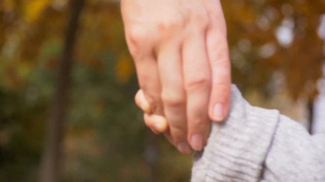 Closeup footage of mothers and baby's hand walking at park