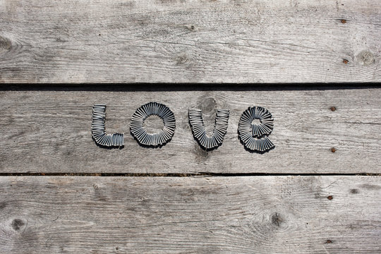 Word LOVE written by metal nails on wooden background