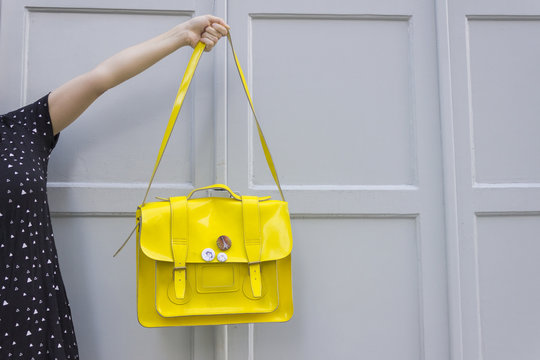 Young caucasian female holding yellow purse against grey background