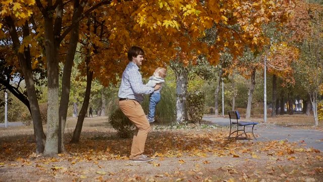 Slow motion footage of happy young father throwing his baby son at autumn park