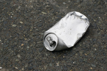 Crumpled can for beer without labels on the sidewalk