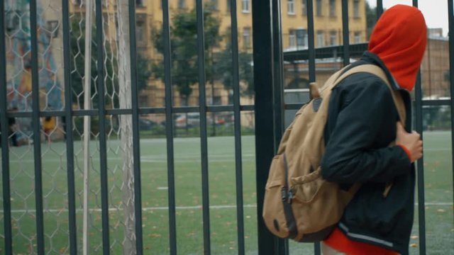 Young student teenager boy's legs in grey sports trousers and sport sneakers shoes walk to the play ground in the backyard of apartment house in old city district