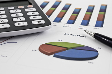 Pie chart and histogram with pen and calculator on the table. Picture taken in studio with soft-box.
