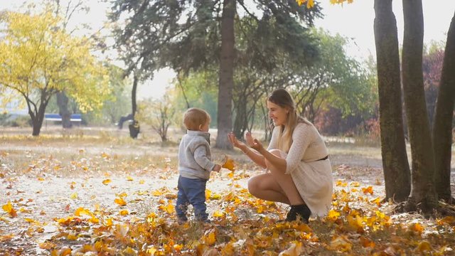 Slow motion footage of happy young mother teaching her baby son walking at park