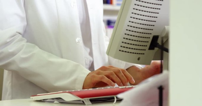 Pharmacist making prescription record on computer in pharmacy
