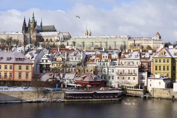 Obraz premium Snowy freeze Prague Lesser Town with gothic Castle above River Vltava, Czech republic