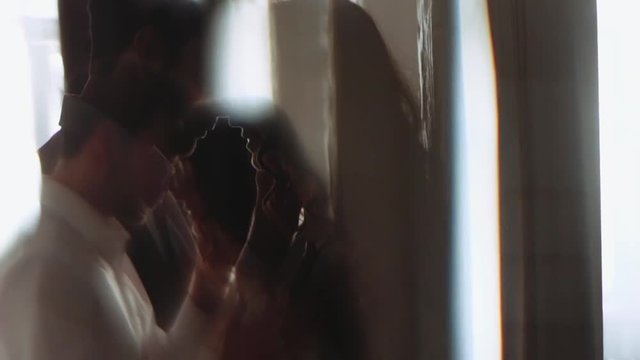 Young bearded man and curly attractive woman. Close up view of a passionate kiss. She is standing by the wall, he comes to her and gives a hot kiss. Couple goals, romantic date, forever in love.